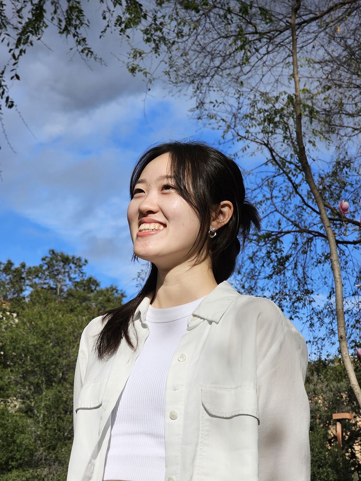 Side photo portrait of Sarah Yun wearing a white shirt in bright scenery looking diagonally